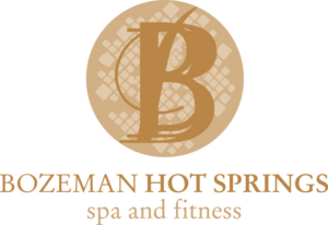 Logo for Bozeman Hot Springs spa and fitness, featuring a large stylized B over a patterned gold circle, with the business name written below in gold and brown text.