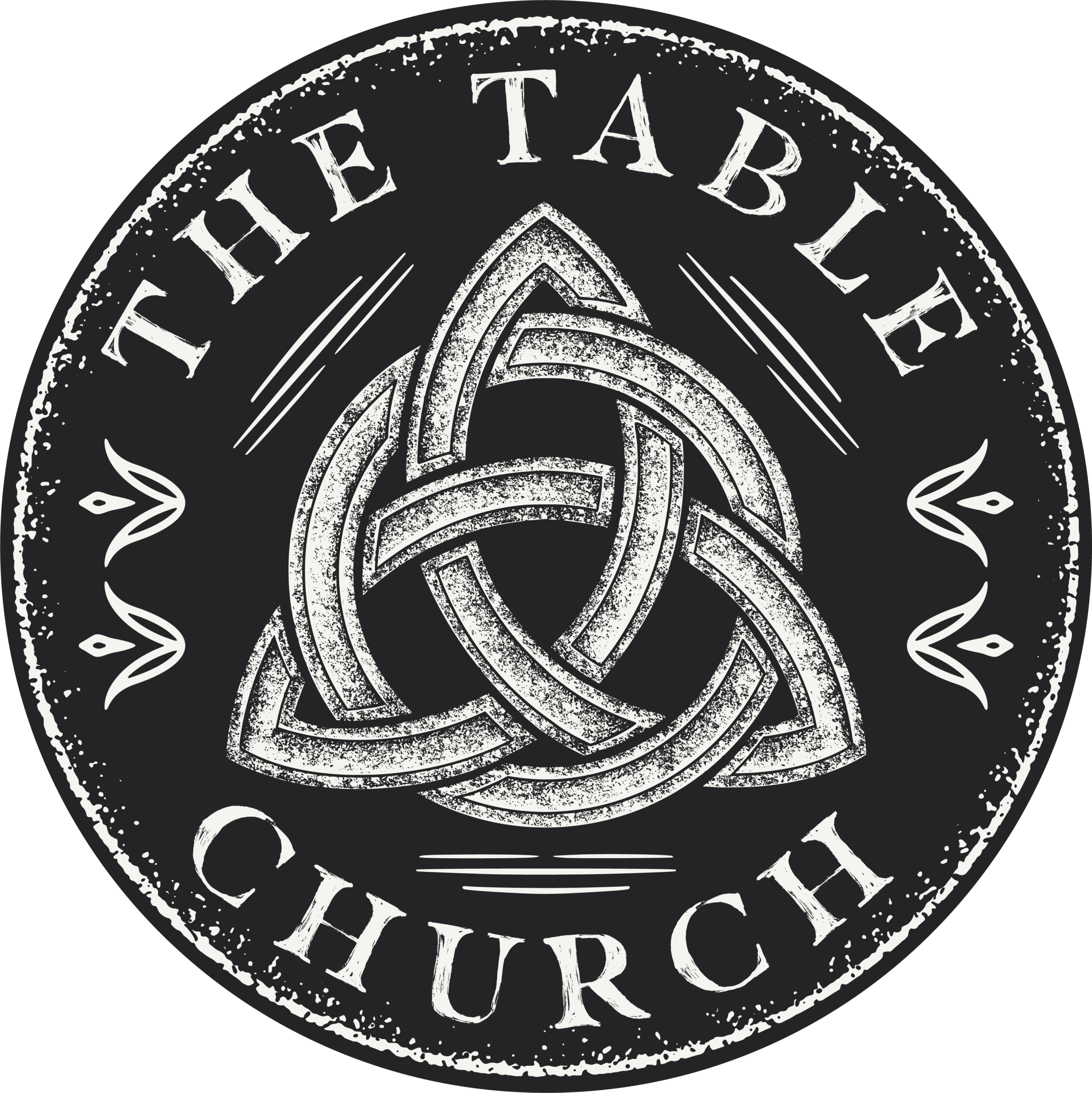 Circular logo for The Table Church featuring a white Celtic knot design in the center on a black background, with decorative lines and flourishes around the knot.